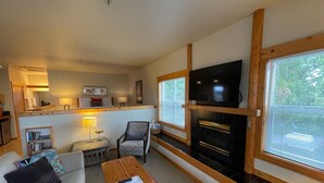 Ein gemütliches Wohnzimmer mit einer Couch, einem Holztisch, einem Fernseher und einem Kamin.
