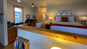 Ein Hotelzimmer mit Bett, Schreibtisch, Fenster und einer Küchenzeile.