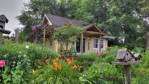 A quaint house surrounded by lush greenery and vibrant flowers. - It's Another Beautiful Day At Captain's Cove in Langley, On Whidbey Island (Langley)
