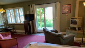 A living room with a large window, a fireplace, a sofa, a television, and a bathtub. - It's Another Beautiful Day At Captain's Cove in Langley, On Whidbey Island (Langley)