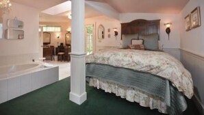 A bedroom with a large bed, a sitting area with a table and chairs, and a bathtub. - It's Another Beautiful Day At Captain's Cove in Langley, On Whidbey Island (Langley)