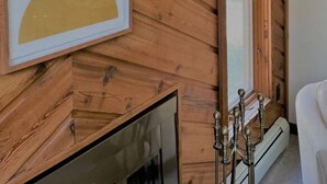 A room with a wooden wall panel, a fireplace, a large mirror, and a framed abstract artwork. - Beach/Ski Home in Harbor Springs (Harbor Springs)