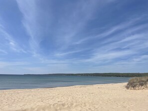 Ein sandiger Strand mit blauem Himmel und ruhigem Wasser.