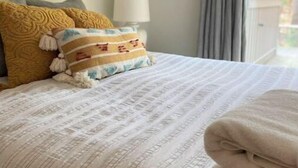 A neatly made bed with striped bedding, two decorative pillows, and a folded blanket. - Beach/Ski Home in Harbor Springs (Harbor Springs)