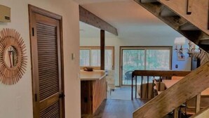 A modern interior with a wooden staircase, a dining area, and a view of the outdoors. - Beach/Ski Home in Harbor Springs (Harbor Springs)