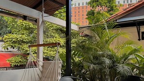 A covered outdoor seating area with a hammock, chairs, and a table with a placemat. - HOTEL  BALI AT POBLADO (Medellín)