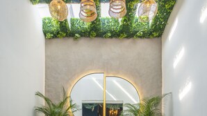 A modern lounge area with a round mirror, two sofas, a small table with a statue, and a patterned floor. - HOTEL  BALI AT POBLADO (Medellín)