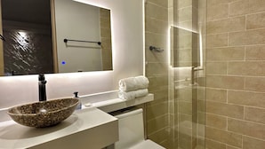 A modern bathroom with a glass shower enclosure, a white sink with a decorative bowl, and a toilet. - HOTEL  BALI AT POBLADO (Medellín)