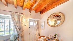 Una habitación acogedora con techo de madera, un ventanal con cortinas, una mesa de comedor con alimentos para el desayuno y un espejo en la pared.