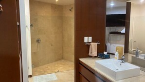 Un baño moderno con cabina de ducha a ras de suelo, un espejo grande y un mueble de tocador con lavabo.