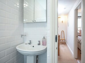 Un bagno con piastrelle bianche, un lavandino bianco e uno specchio sopra.