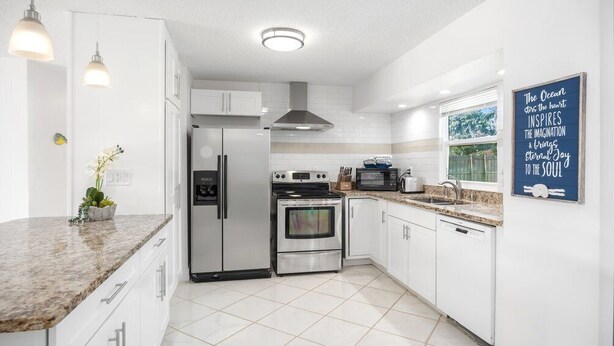 A modern kitchen with white cabinetry, stainless steel appliances, and a granite countertop.