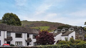 A row of traditional white houses with stone facades, set against a backdrop of rolling hills. - 2 bedroom accommodation in Ambleside (Ambleside)
