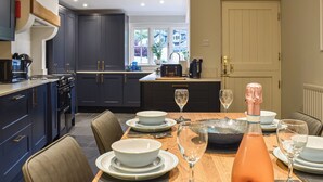A modern kitchen with dark cabinets, a dining table set with plates, glasses, and a bottle of rosé wine. - 2 bedroom accommodation in Ambleside (Ambleside)