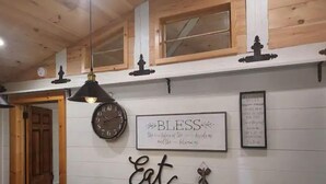 Un interior de madera con un reloj, un letrero que dice 'Bless Eat' y un menú enmarcado en la pared.