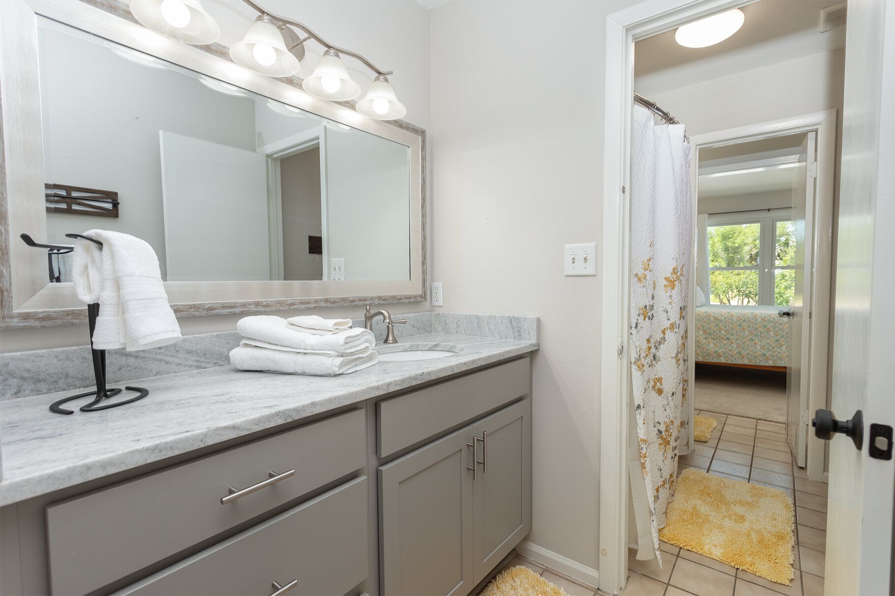 Un bagno con top in marmo, lavabo, specchio e porta asciugamani.