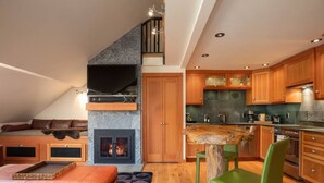 A loft-style living space with a fireplace, a dining area, and a kitchen. - The Ikon | Lofted Studio with King Bed + Patio (Whistler)