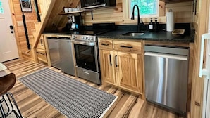 Une cuisine compacte dotée de meubles en bois, d’appareils électroménagers en acier inoxydable et d’une fenêtre offrant une vue sur la verdure.