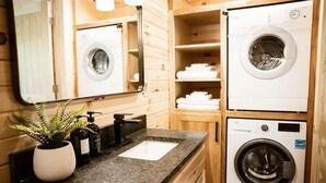Une petite salle de bain comprenant un lavabo, un miroir et deux machines à laver superposées.