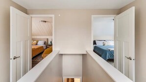 Een kamer met hoge plafonds en een schuine hemel, verlicht door een centraal hanglamp.
