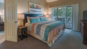 A bedroom with a large bed, a nightstand, a lamp, a dresser, and a television. - Branson Vacation Rental w/ Pools & Hot Tub! (Branson)
