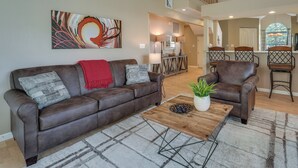 A spacious living area with a brown leather sofa, a wooden coffee table, and a large abstract painting on the wall. - Branson Vacation Rental w/ Pools & Hot Tub! (Branson)