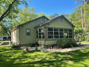 A two-story house with a front porch, large windows, and a lawn.