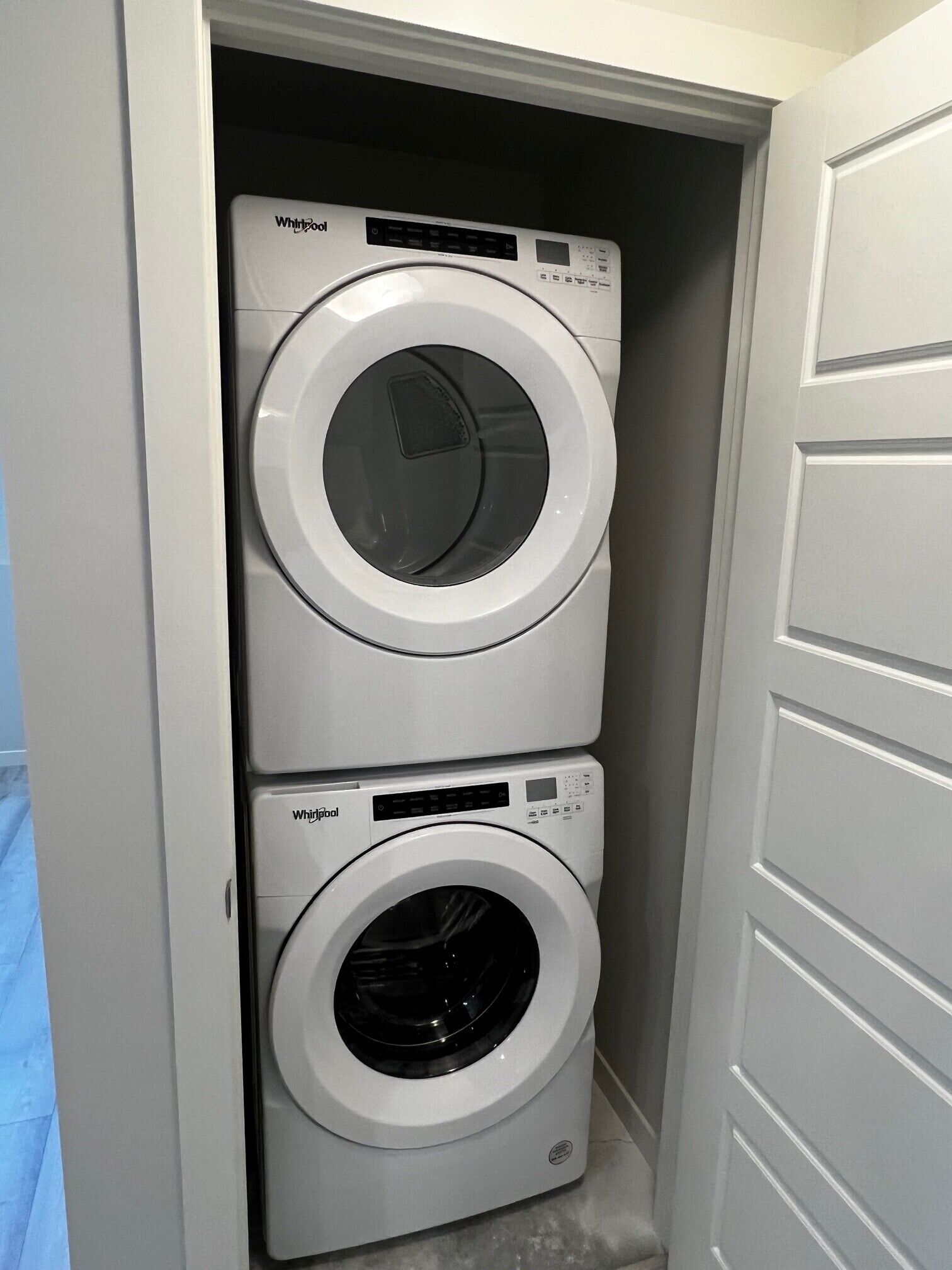 A compact laundry room with two stacked front-loading washing machines.