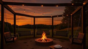 Een overdekt terras met zitplaatsen, een vuurkorf en lichtjes.