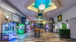 Un hall d’hôtel avec des jeux d’adresse à saisir, un comptoir d’accueil et un espace repas.