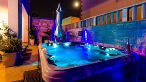 A hot tub with blue lighting, surrounded by potted plants and a stone wall. - Villa Aura - Executive Business room (Dubrovnik)
