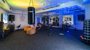 Un gimnasio con un saco de boxeo, equipo de ejercicio y una frase motivacional en la pared.