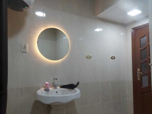 Un baño con un espejo redondo, un lavabo y una puerta.