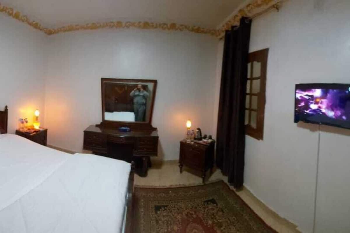 A hotel room with a bed, a dresser, a television, and a door.