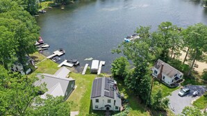 An aerial view of a lakeside property with a house, dock, and boats.