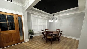 Un coin repas avec une table et des chaises en bois, une plante en pot et un luminaire suspendu au plafond.