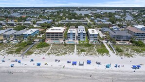 An aerial view of a coastal hotel with multiple buildings, a beach with umbrellas, and a marina in the background. - NEW! 2/2, IRB-Beach/Pool View, Sleeps 6, unit F (Indian Rocks Beach)