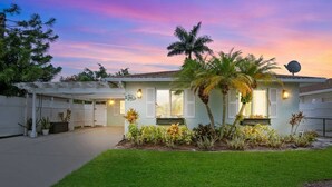 A two-story house with a covered patio, palm trees, and a well-maintained lawn. - Coastal Retreat w/ Porch, Games, Pet Friendly! (Naples)