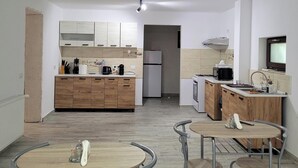 Una cocina moderna con armarios de madera, horno empotrado y microondas. Hay un comedor con una mesa redonda y sillas.