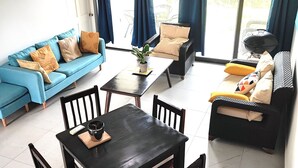 En stue med en blå sofa, et sort spisebord med fire stole, og en sort sofa med gule puder.