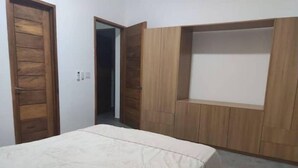 Un dormitori amb llit, armari de fusta i prestatges integrats.