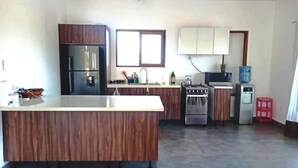 A modern kitchen with a central island, stainless steel appliances, and wooden cabinetry. - 2 bdrm Villa, walk to square (pedasi)