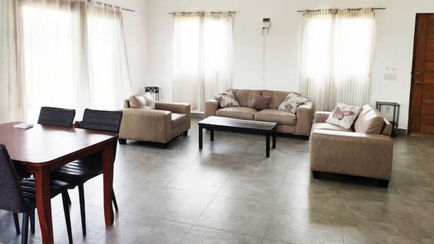 A living room with a sofa set, a coffee table, and a dining table with chairs. There are two ceiling fans and a door visible. - 2 bdrm Villa, walk to square (pedasi)
