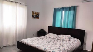 A bedroom with a bed, curtains, a painting, and an air conditioning unit. - 2 bdrm Villa, walk to square (pedasi)