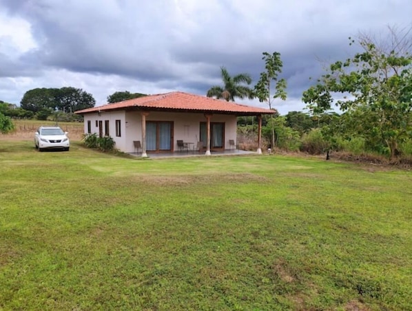 A single-story house with a red-tiled roof, a covered porch, and a car parked in front.