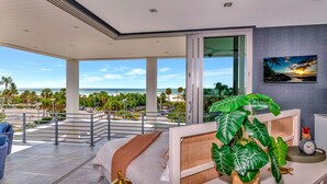 A modern hotel room with a balcony overlooking a beach, a large plant, and a painting on the wall. - Pirate House: Gulf Front, Pool, #1 Location Lido Key, St. Armands One Block. (Sarasota)
