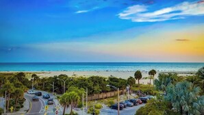 A beach with a clear sky, palm trees, and parked cars. - Pirate House: Gulf Front, Pool, #1 Location Lido Key, St. Armands One Block. (Sarasota)