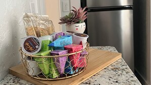 Una encimera de cocina con una cesta de bocadillos envasados y coloridos y una planta suculenta en maceta.