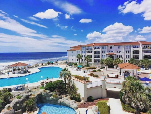 Guests can enjoy a refreshing swim in the resort's large pool surrounded by lush greenery and scenic views of the adjacent beach.