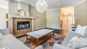 Ein Wohnzimmer mit Kamin, einer Couch, einem Couchtisch und einer Hängeleuchte.